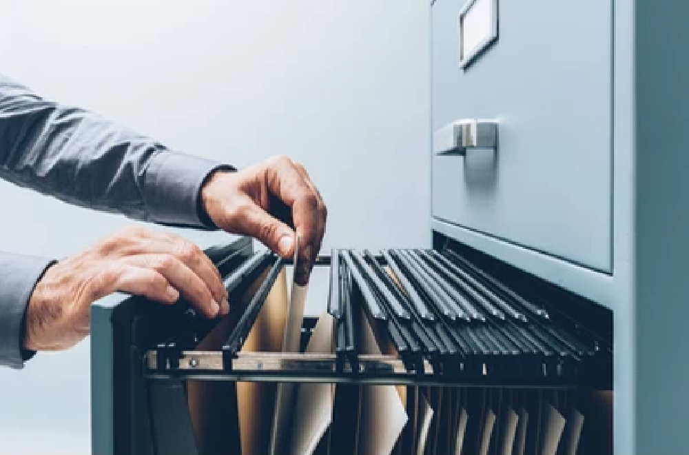Office clerk searching for files into a filing cabinet drawer close up